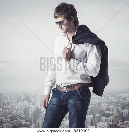 Confident, ambitious good looking man on the top of city with a jacker his shoulder.