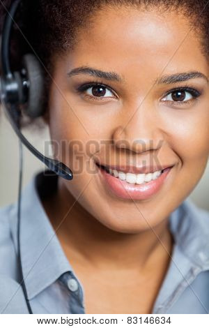 Portrait of young smiling female customer service representative wearing headset in office