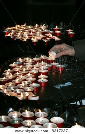 Elderly Woman In Prayer And Lit A Candle In The Church