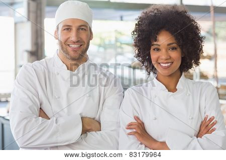 Team of bakers smiling at camera in the kitchen of the bakery