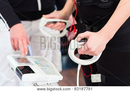 Female coach controlling results after ems electro muscular stimulation training with body fat measuring
