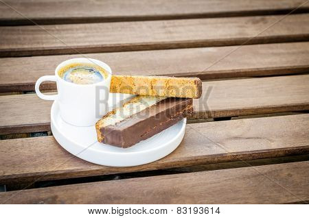 A cup of coffee with biscotti.