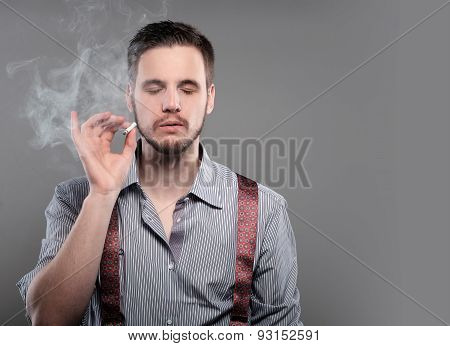 Fashion Man Smoking A Cigarette On Gray Background.