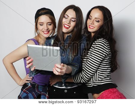 Three girls friends taking selfie with digital tablet, studio shot over gray vackground