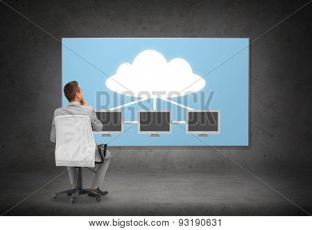 business, people, transferring data and technology concept - businessman in suit sitting in office chair over screen with cloud and server computers on gray wall background from back
