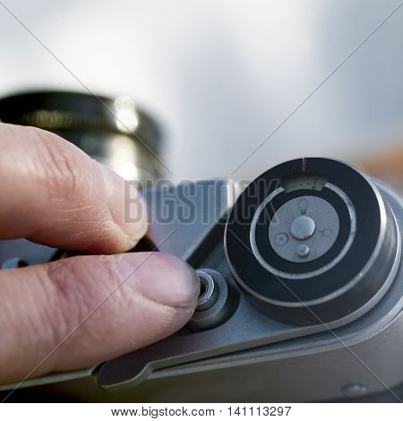 Cropped shot of a human finger about to press a shutter release button on a retro looking photo camera shallow depth of field
