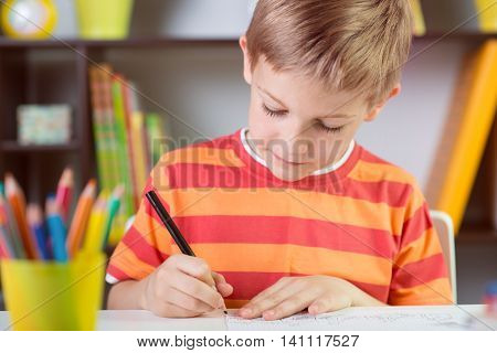 School Boy At Classroom Desk Making  Schoolwork