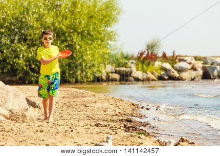 Play and fun concept. Little playful enjoyable boy kid throwing frisbee disc. Male child having fun playing outdoor on beach.
