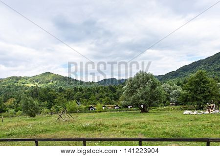 Photo of small wooden houses on green fields Romania.