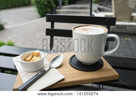 hot fresh coffee in white cup on black table on wooden tray biscuit cookie and silver spoon and white saucer cappuccino coffee mocha coffee espresso coffee latte coffee