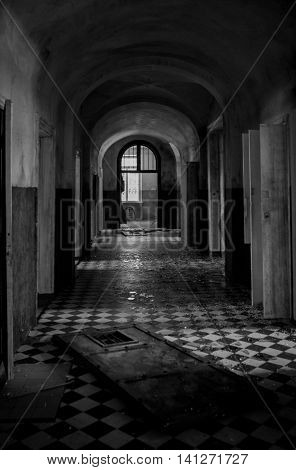 Abstract image of a dark spooky corridor in an old abandoned hospital building with shatter on the checkered floor