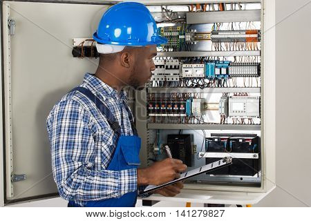 Male Technician Holding Clipboard While Examining Fusebox