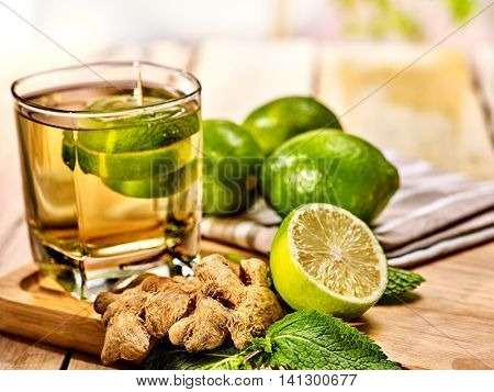 Healthy detox drink with ginger . On wooden boards glass with green tea and mint. Mint ginger drink number three hundred thirty five with half lime .