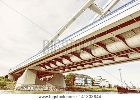 Modern Apollo bridge in Bratislava Slovak republic. Yellow photo filter. Architectural theme. Ship transportation. Infrastructure theme. Danube river.