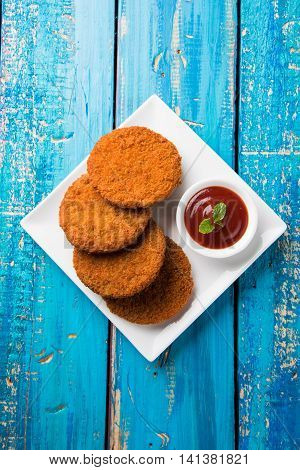 Indian chat item aloo or aalu tikki or tikiya or fried potato cake also known as ragda patties served with tomato ketchup, selective focus