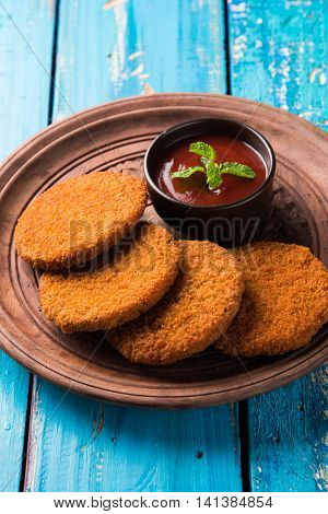 Indian chat item aloo or aalu tikki or tikiya or fried potato cake also known as ragda patties served with tomato ketchup, selective focus