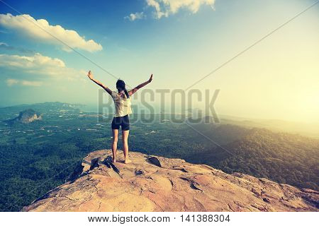 young freedom woman open arms on mountain peak
