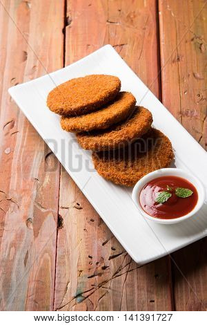 Indian chat item aloo or aalu tikki or tikiya or fried potato cake also known as ragda patties served with tomato ketchup, selective focus