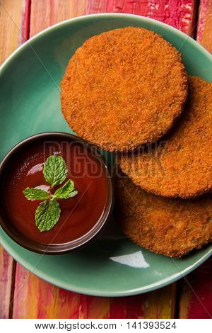 Indian chat item aloo or aalu tikki or tikiya or fried potato cake also known as ragda patties served with tomato ketchup, selective focus