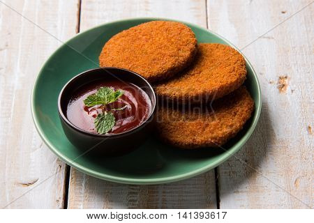 Indian chat item aloo or aalu tikki or tikiya or fried potato cake also known as ragda patties served with tomato ketchup, selective focus