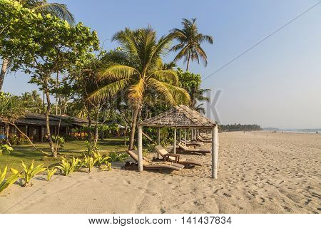 Coconut palm leafs on a perfect beach and sun beds for tourists. Concept travel and holiday in Asia Myanmar