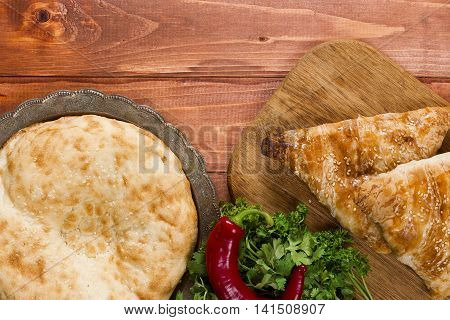 Traditional Uzbek bread and samosas on wooden background