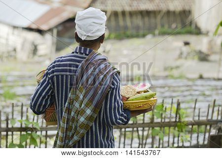Balinese man bringing traditional offering to Hindu Temple in Trunyan Bali Indonesia.