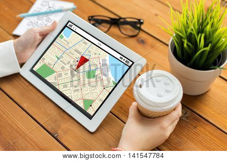 business, navigation, technology, people and advertisement concept - close up of woman with gps navigtor map on tablet pc computer screen and coffee cup on wooden table