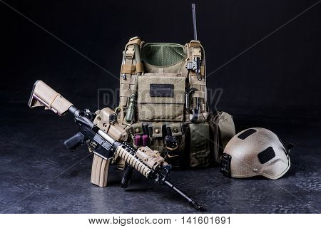 Assault riflebulletproof vesthelmet and other military amunitions on black background