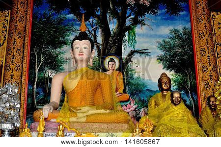 Chiang Mai Thailand - December 26 2012: Statue of seated Buddha with devoted Monks wrapped in yellow robes at Wat Chedi Liem