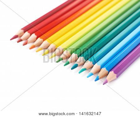 Multiple colorful color pencils composition arranged in a line to form a rainbow gradient, composition isolated over the white background, close-up crop fragment