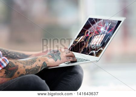 Young man with tattoo using laptop on a floor at home