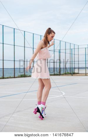 Attractive young woman on roller skates standing and having fun at the plaground