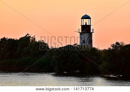 Abandoned old and weathered lighthouse at sunet on a river