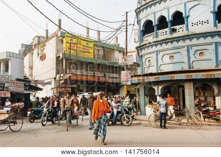 LUCKNOW, INDIA - JAN 31, 2013: Poor people walking on indian street with blue houses and bikes driving around on January 31, 2013. Lucknow with population of 6000455 is the largest city of Uttar Pradesh