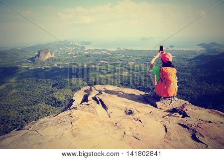 young woman hiker use smartphone taking photo on seaside mountain top
