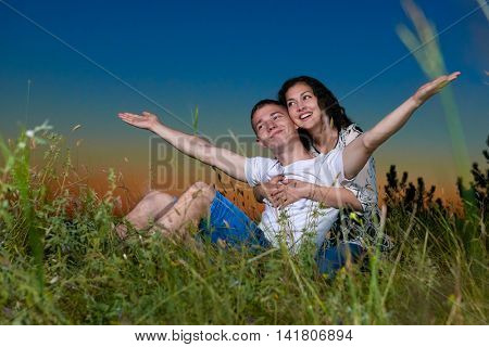 young romantic couple open arms and having fun at sunset on outdoor, dark night sky, love tenderness concept, young adult people