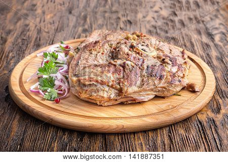 Medium rare grilled Beef steak Ribeye with onion on cutting board on dark wooden background. Horisontal