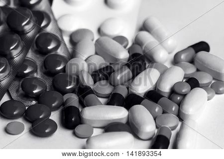 pile of medicines for various purposes are on a blue background,  packaged and without,  black and white photo
