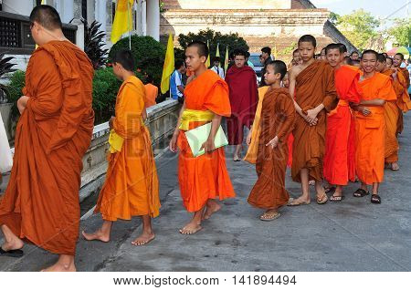 Chiang Mai, Thailand - December19, 2012: Barefoot novitiate teenage monks wearing orange robes entering the ubusot sanctuary hall for morning prayer at Wat Chedi Luang