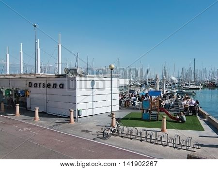 PALMA DE MALLORCA BALEARIC ISLANDS SPAIN - APRIL 2 2016: Darsena outdoor seaside cafe with people in sunshine Palma de Mallorca Balearic islands Spain on April 2 2016.