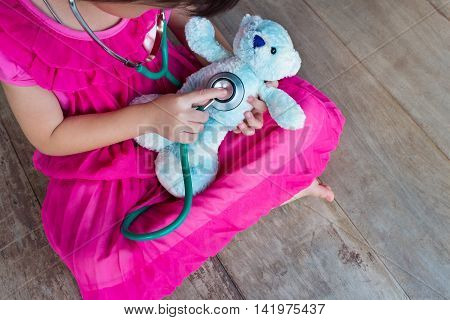 Top View Of Child Playing Doctor Or Nurse With Plush Toy Bear At Home.