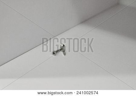 Closeup Of Two Iron Screws On White Wooden Shelf