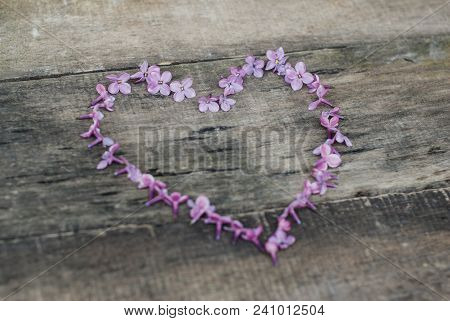 Spring Flowers. Lilac Flowers Frame Heart Shape Textured Rustic Gray Wooden Background.