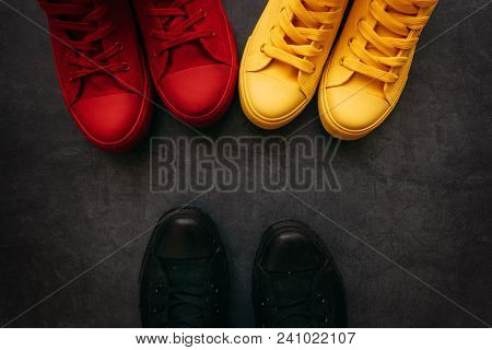 Youth Confrontation Conceptual Image. Young People In Colorful Sneakers Confronting A Person In Blac