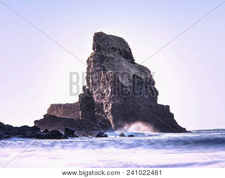 Sea Stack Sharp Silhouette By Sunset Sky. Evening Light On The Rocks, Boulders And Cliff Face Of Tal