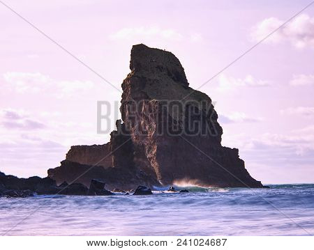 Cloudy Evening On Rocky Shore At Sunset. Sunset Mirroring In  Sea Water And Large Cracked Rocks With