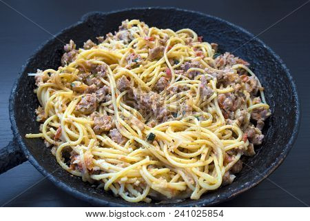 Appetizing Spaghetti In An Old Frying Pan With Bolognese Sauce On A Dark Background Close Up