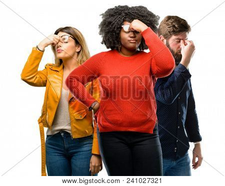 Group of three young men and women with sleepy expression, being overworked and tired, rubbes nose because of weariness