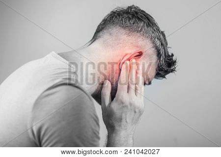 Male Having Ear Pain Touching His Painful Head Isolated On Gray Background